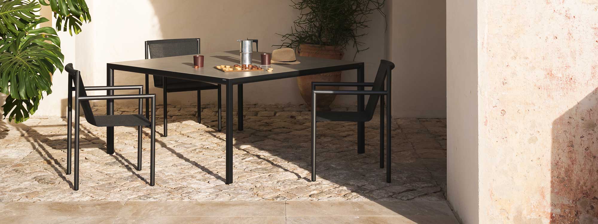 Image of Plein Air minimalist garden chairs and large square dining table by RODA, in sun and shade of hot rustic terrace