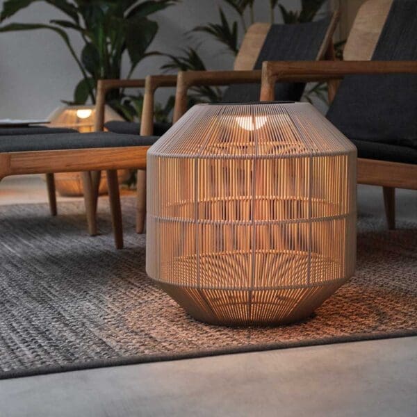 Image of illuminated Nest garden lantern next to Gloster teak furniture