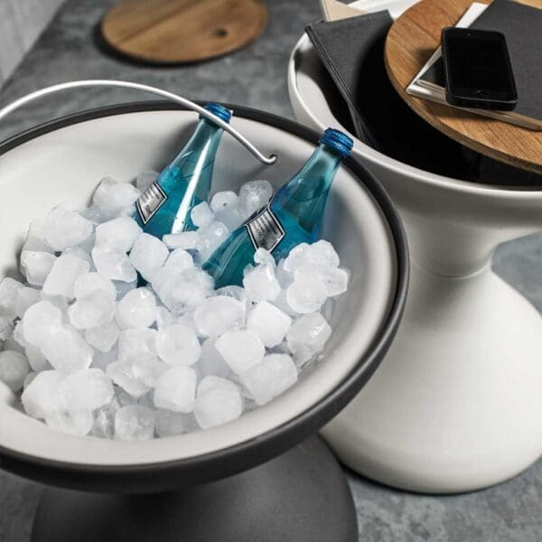 Image of detail of interior of Bells modern ice bucket by Gloster loaded with ice cubes and blue bottles of sparkling water