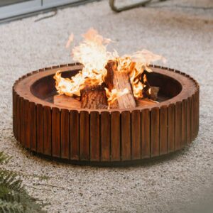 Image of flames dancing within The Ring modern corten fire pit, shown on gravel surface