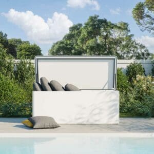 Image of Conmoto Ronda white garden cushion chest with lid open, shown on decking with swimming pool in the foreground