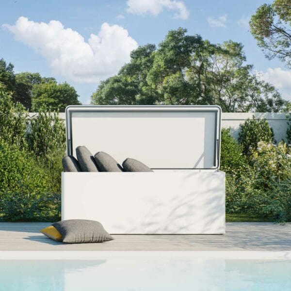 Image of Conmoto Ronda white garden cushion chest with lid open, shown on decking with swimming pool in the foreground