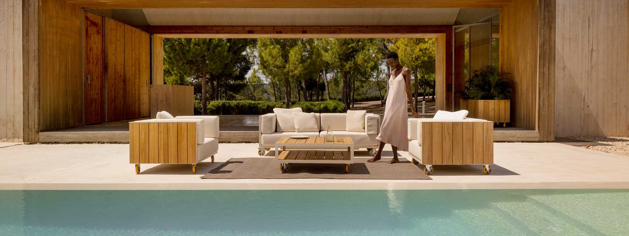Image of woman stood in the sunshine amongst Vondom Vineyard sofa and lounge chairs on sleek poolside