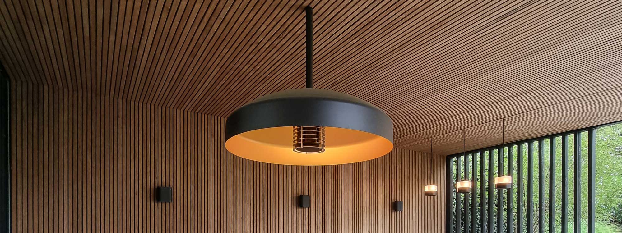 Image of Heatsail Disc Pendant exterior ceiling heater above chic outdoor sofa in wooden-clad garden room