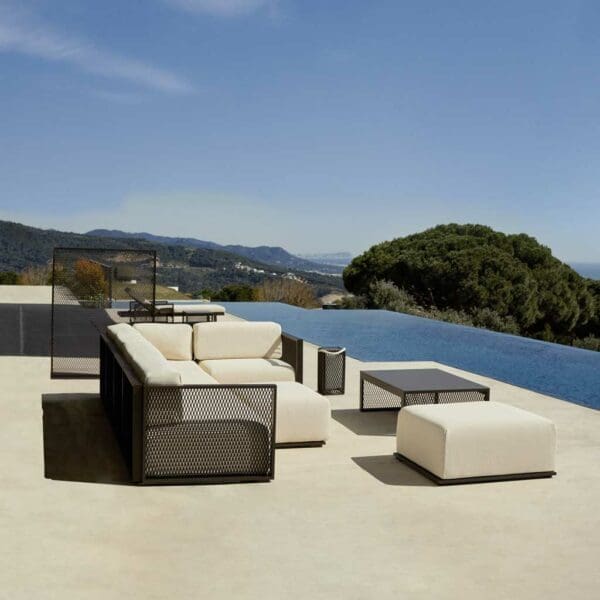 Image of The Factory small outdoor corner sofa by Vondom, with minimalist swimming pool, tree and hills in the background