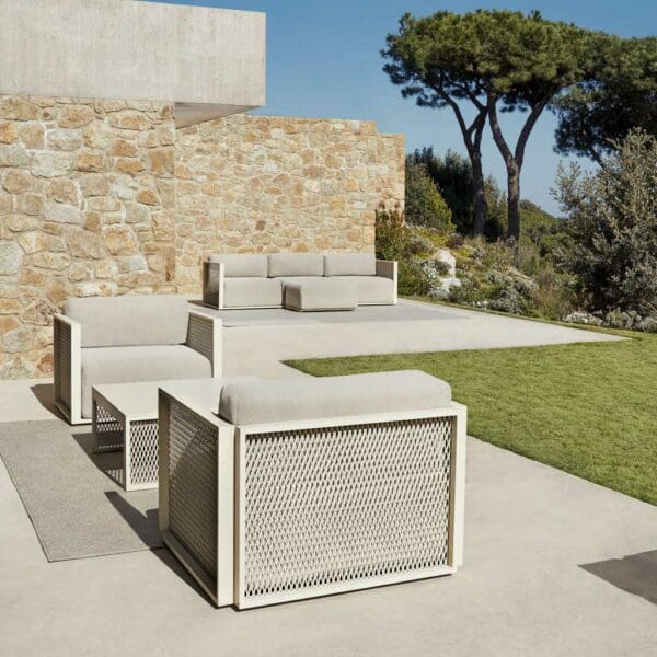 Image of Vondom The Factory contemporary garden lounge chairs and sofa on sunny terrace with rustic stone wall and blue sky and trees in the background