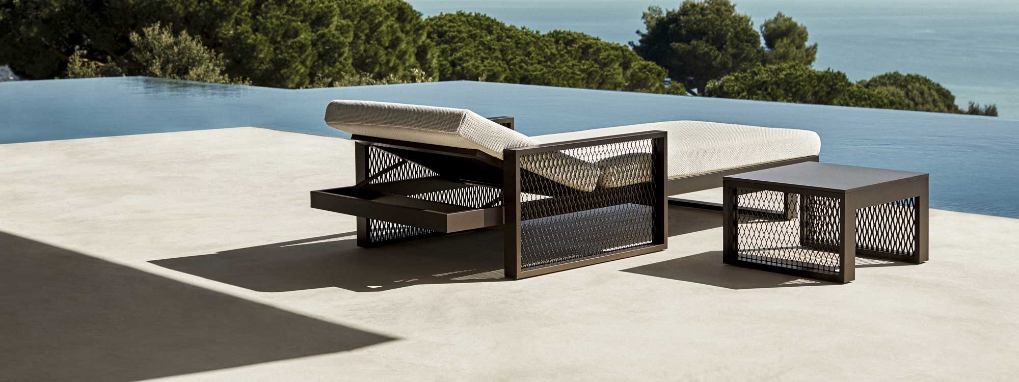Image of Vondom The Factory adjustable sun lounger and side table on terrace with horizon swimming pool and sea in the background