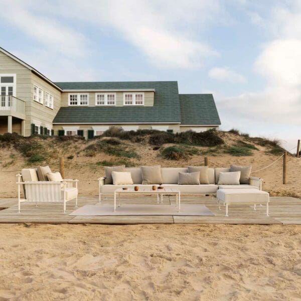 Image of Hamptons sectional corner sofa on wooden deck on the beach, with large weather-boarded house in the background
