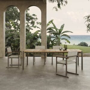Image of Vondom Tulum outdoor dining table & chairs on veranda with archways, banana plants & sea in the background