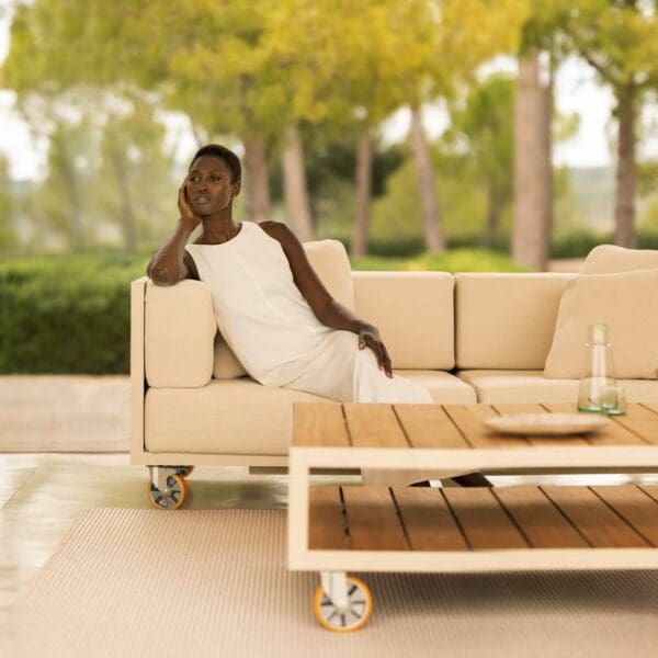 Image of woman sat on Vondom Vineyard garden sofa with wheels with coffee table with wheels in the foreground