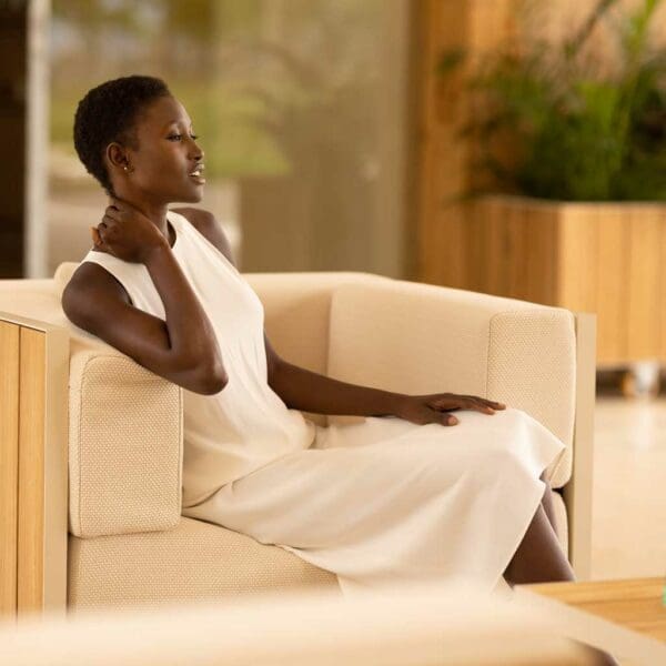 Image of elegant woman in white dress sat in Vondom Vineyard white garden lounge chair with teak surfaces