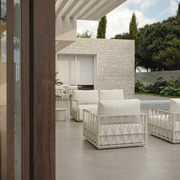 Image of white Ava garden lounge furniture by Oisie wiht pool, linear building and tropical plants in the background