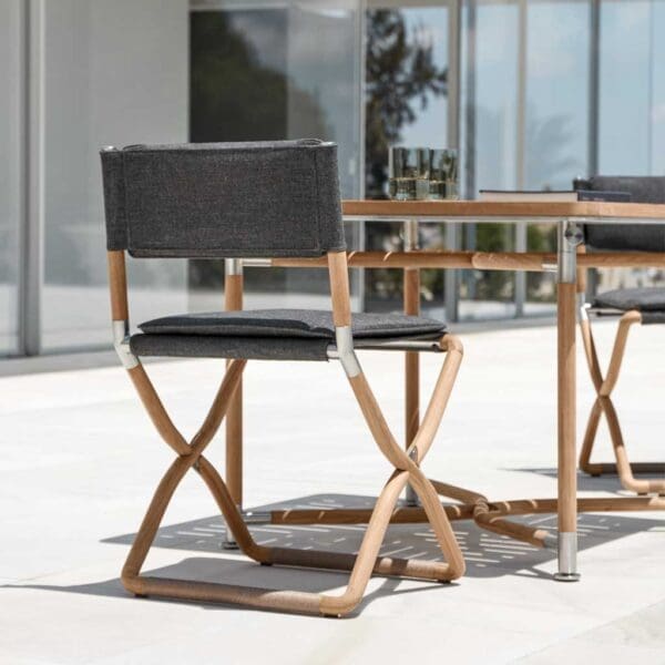 Image of Navigator folding teak table & chairs by Gloster on a sunny modern terrace