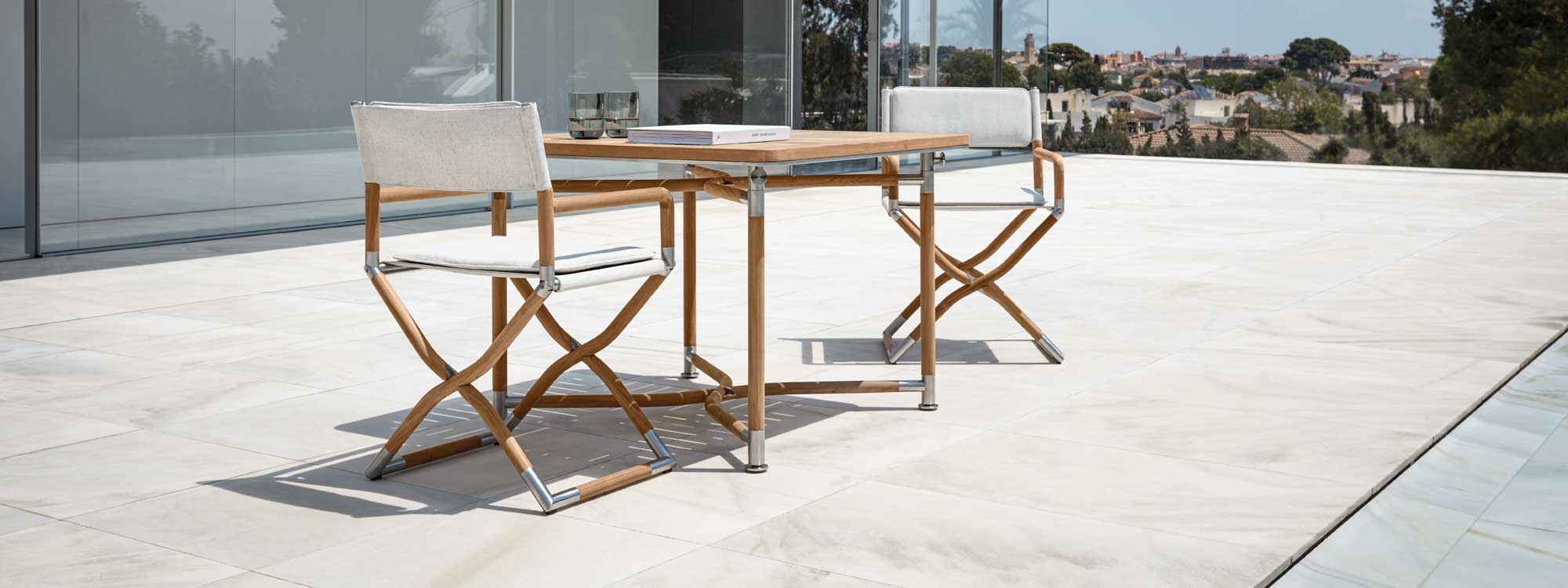Image of pair of Navigator teak director chairs and folding dining table by Gloster on sunny terrace