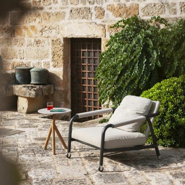 Image of Astra reclining garden chair and Root side table on rustic terrace with shrubs in the background
