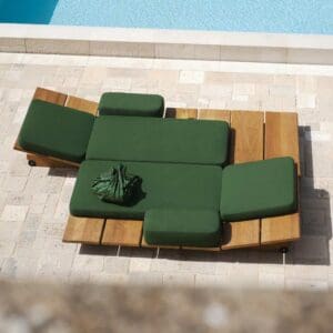 Birdseye view image of pair of Eolie sun loungers side by side, in natural iroko hardwood with green cushions, with inviting swimming pool to the side