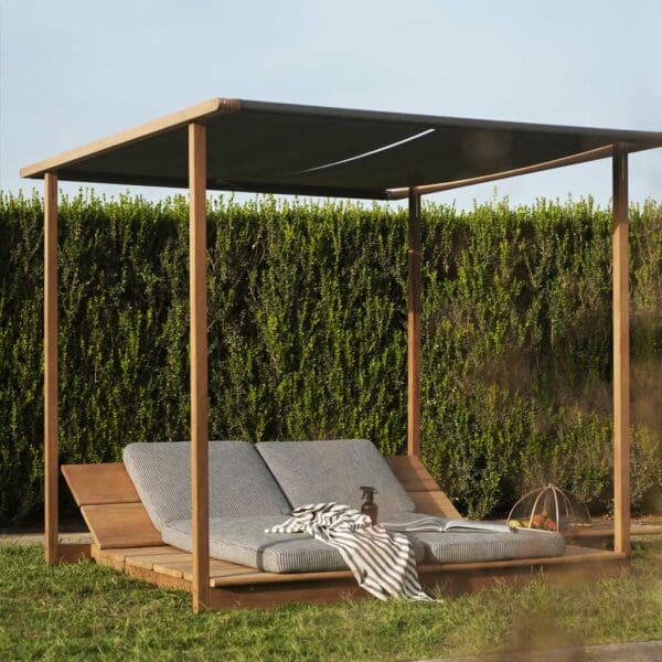 Image of RODA Eolie hardwood pergola and sunbeds on lawn with verdant tall hedge in the background