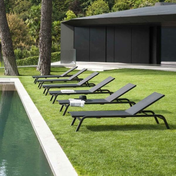 Image of row of RODA Surfer contract loungers on a grass lawn next to a still swimming pool