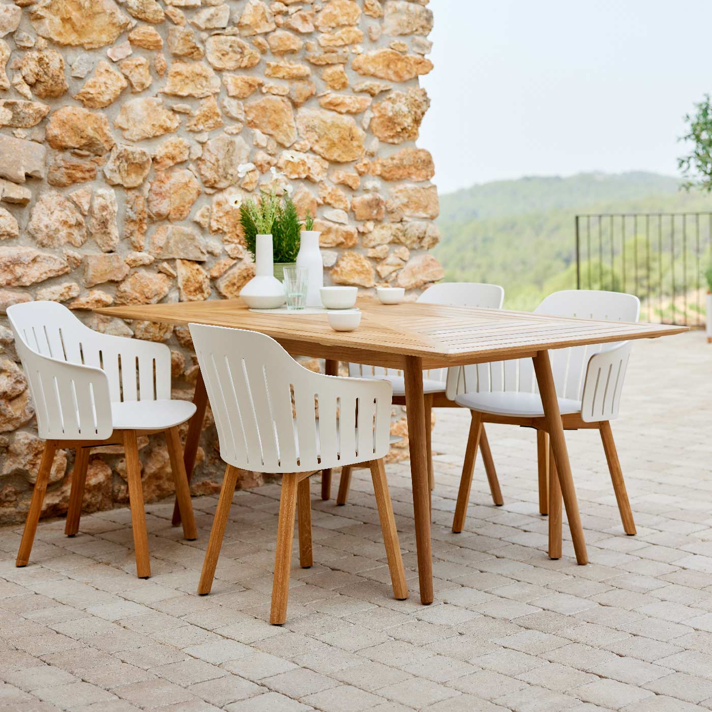 Image of Define rectangular teak table and Choice white recycled garden chairs on rustic terrace