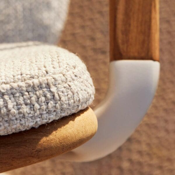 Image of detail of Exes garden armchair's white aluminium frame and teak back and arm, with snug back cushion