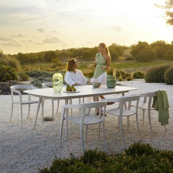 Image of white Styletto table and Jive chairs on sand, surrounded by dunes and grasses in late afternoon sun