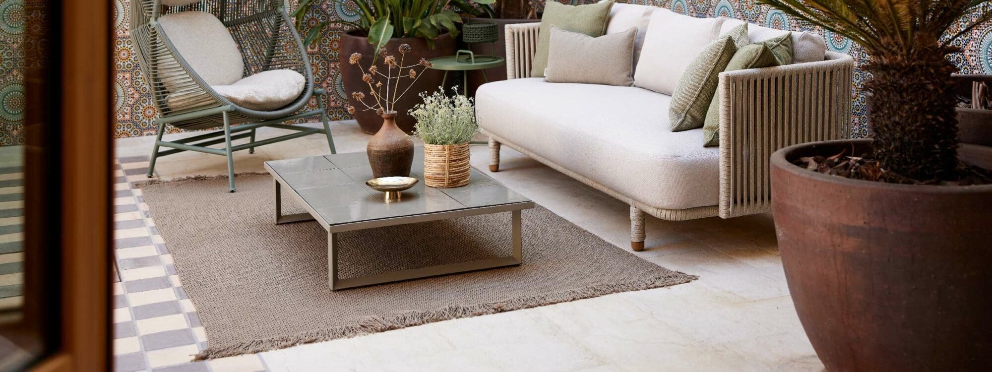 Image of Moments garden sofa and Glaze low table, both placed on Knit outdoor rug by Cane-line