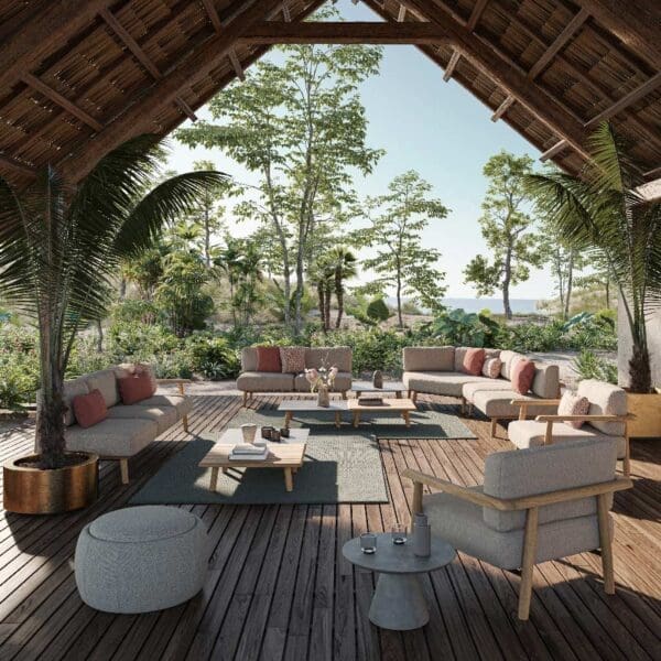 Image of Royal Botania Mambo Lounge teak garden sofas beneath the tall ceiling of a pavilion, with trees and blue sky in the background