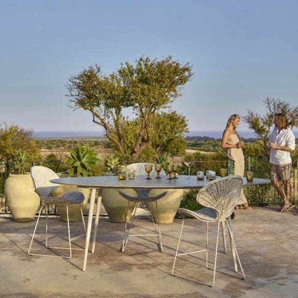Image of Ostrea organically designed outdoor bar stools and Styletto high bar table with women chatting in the background