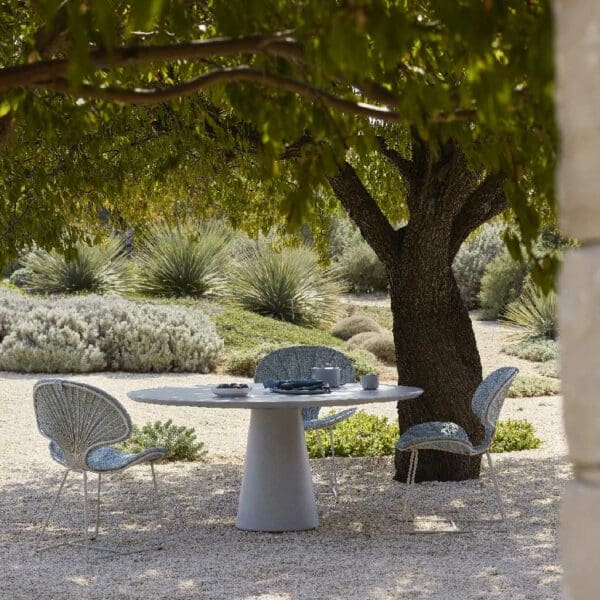 Image of Ostrea modern garden chair and Conix dining table by Royal Botania beneath shady canopy of tree on a sunny day