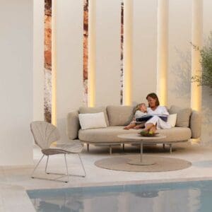 Image of mother and daughter relaxing on Organix garden sofa with pair of Ostrea lounge chairs and swimming pool in the foreground