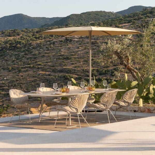 Image of Ostrea low garden chairs, Styletto low dining table and Palma parasol in natural taupe tones, with arid hillside in the background