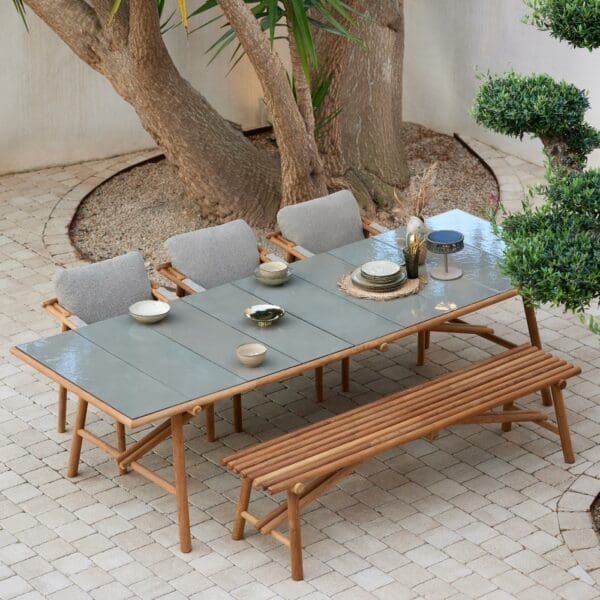 Image of bird's eye view of Sticks teak dining set with glazed lava stone table top, with trunk of large tree in the background