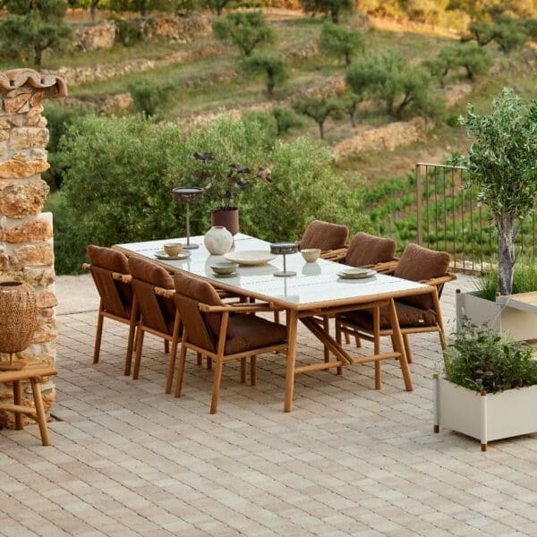 Image of Sticks teak table and chairs with Umber Brown cushions on rustic terrace in early evening shade