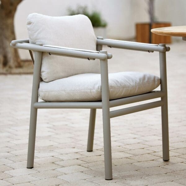 Image of Cane-line Sticks taupe garden armchair with plump cream coloured back and seat cushions