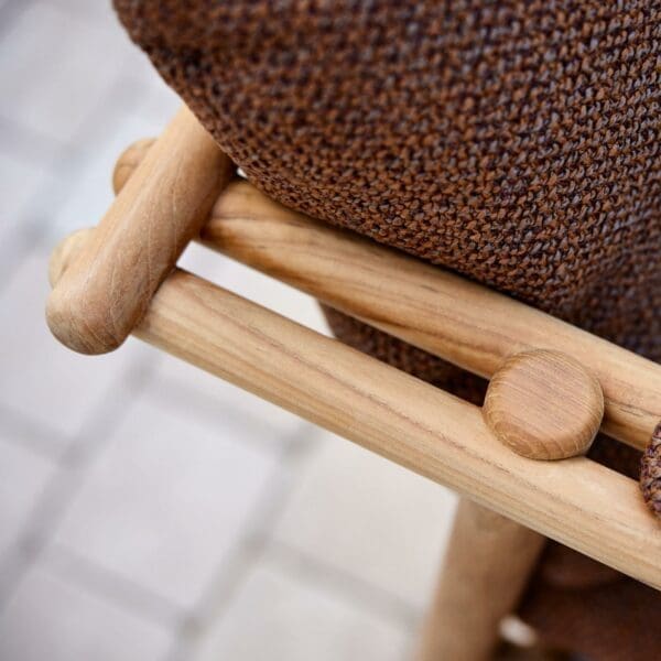 Image of detail of Sticks chair's circular teak profiles and Umber Brown cushions, by Cane-line
