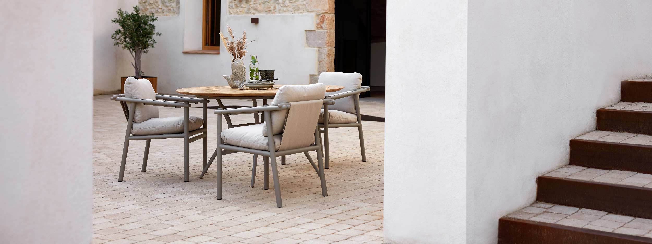 Image of Sticks aluminium armchairs around Joy circular garden dining table by Cane-line