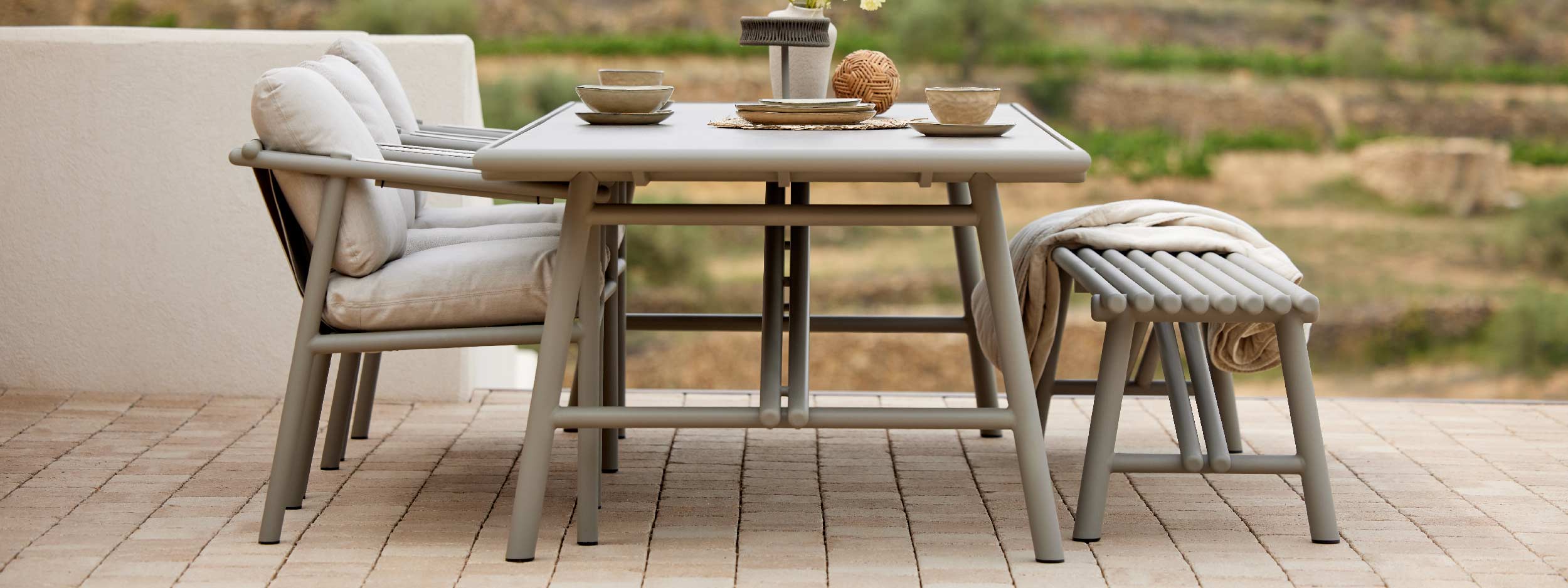 Image of Cane-line Sticks modern garden table and chairs on terrace with arid countryside in the background