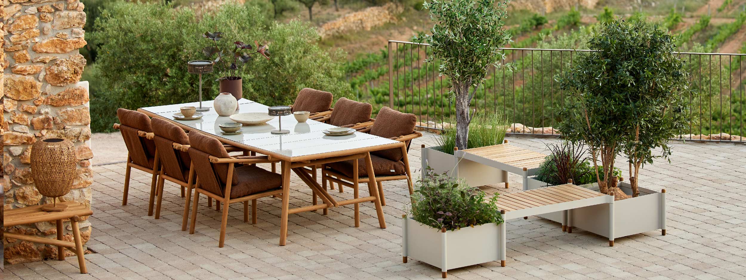 Image of Cane-line Sticks teak dining furniture and Sticks planters and benches on rustic terrace