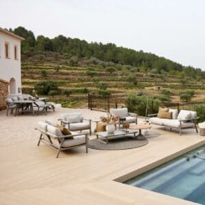 Image of Cane-line Sticks taupe garden sofa and lounge chair on poolside with villa & arid terraced hillside in the background