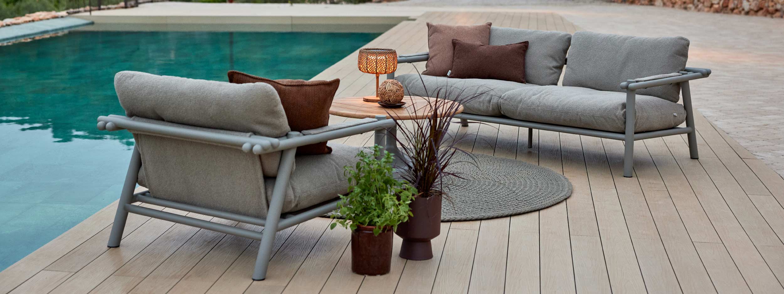 Image of Sticks taupe garden sofa and lounge chair, together with Glaze coffee table on decked poolside