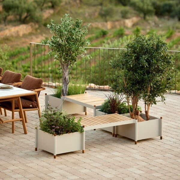 Image of Sticks modern plant pots and bench seats in sand powder coated aluminium and teak, with Sticks teak dining furniture in the background