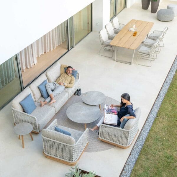 Image of couple lounging on Acri teak sofa and easy chair on minimalist terrace, with Alden garden chairs in the background