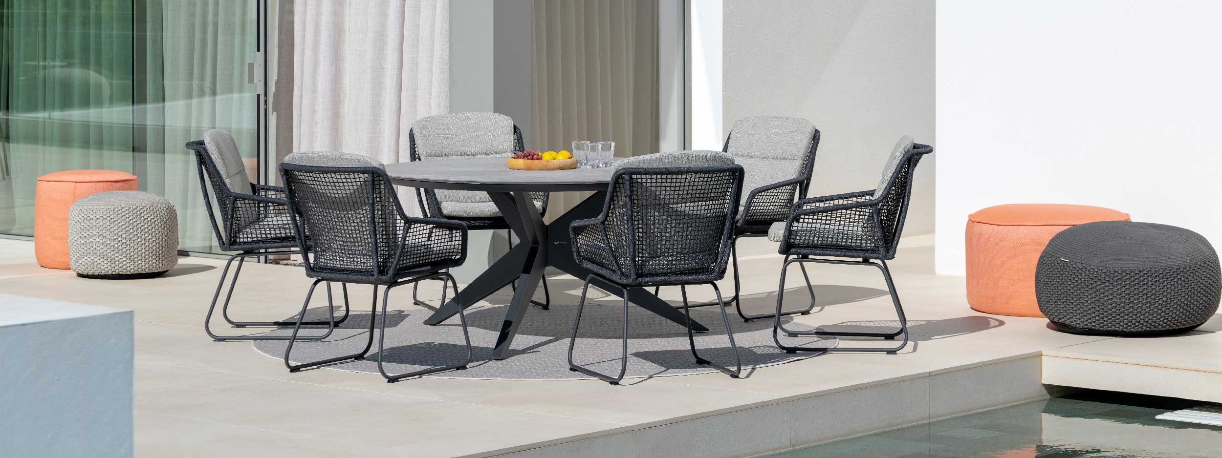 Image of Yate round ceramic garden table and Alden charcoal coloured dining chairs