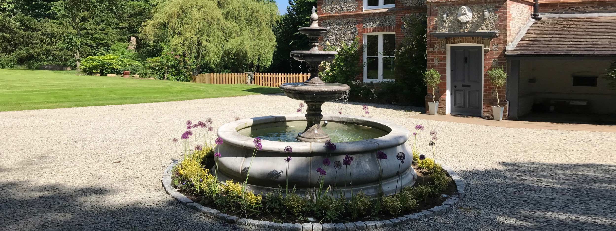Image of large tiered water fountain by Geoffs Garden Ornaments, shown on driveway of luxury home