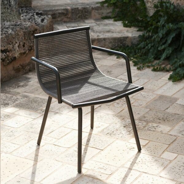 Image of RODA Laze garden armchair casting shadows on stone terrace