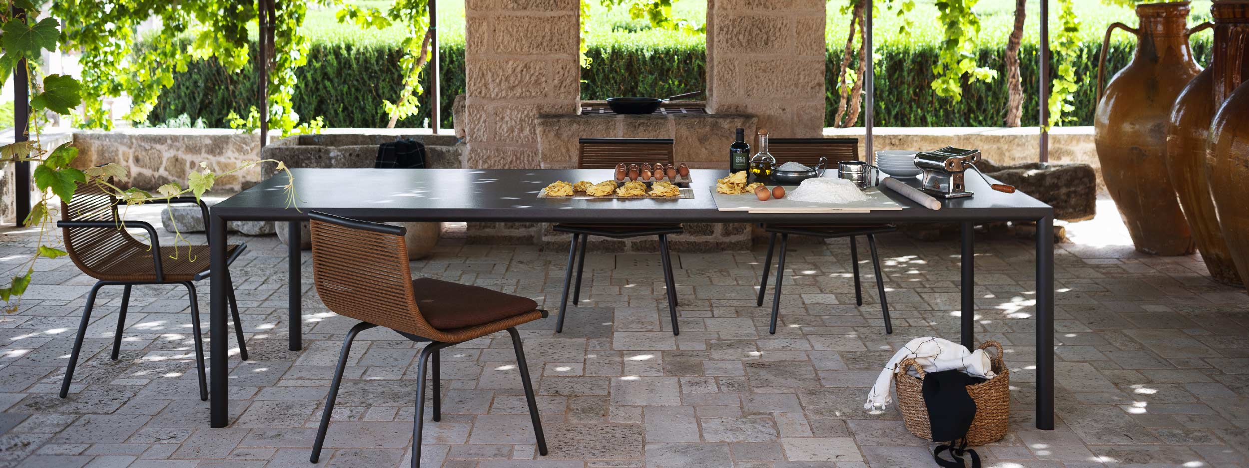 Image of Laze garden dining chairs, shown with or without arms, placed around Plein Air minimalist garden dining table