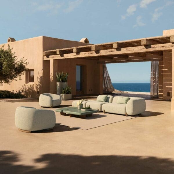 Image of Milos minimalist upholstered garden sofa and lounge chairs on sunny terracotta coloured terrace, with blue sea and sky in the background