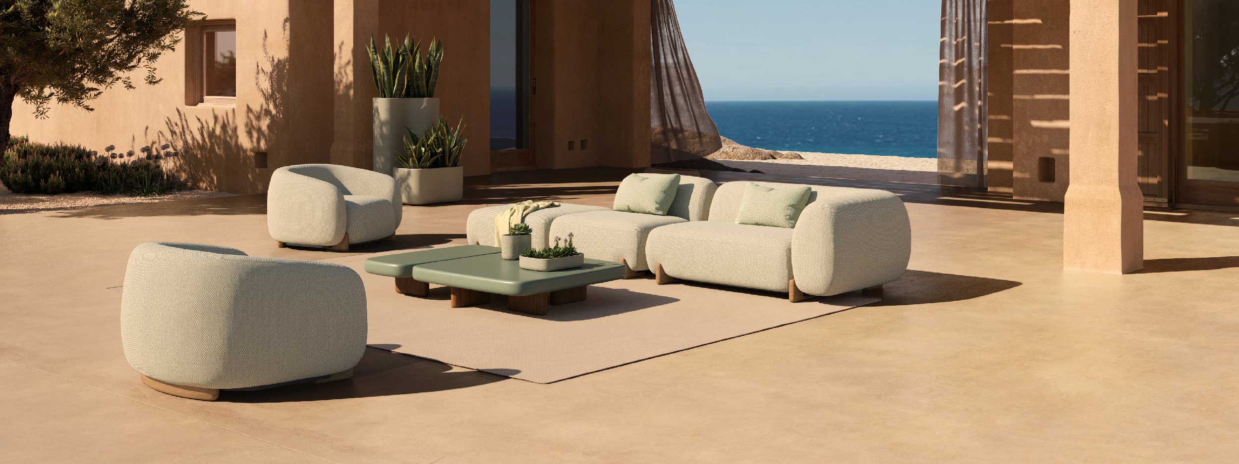 Image of Milos sectional garden sofa and upholstered outdoor lounge chairs in sunny courtyard, with drapes billowing in the background and inviting blue sea beyond