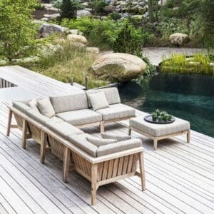 Image of Gommaire Copenhague teak corner sofa and ottoman on decking next to inviting natural swimming pool