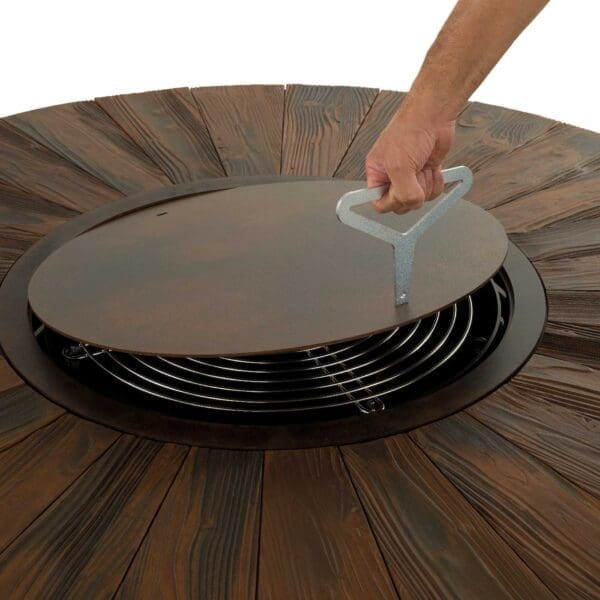 Studio image of someone lifting the cover plate from Zero textured corten steel fire plate by AK47 Design, Italy.